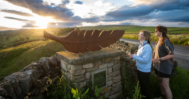 Two women admiring sunset over countryside from Whistle Cragg in the Durham Dales.